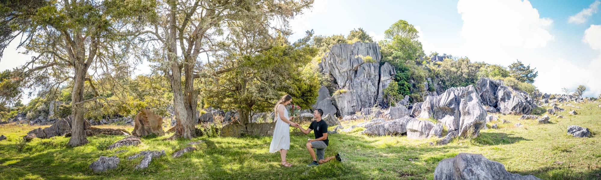 A man proposes to a woman who has a white dress and flowers, by the limestone cliffs at Lake Waro, Hikurangi, Whangārei. 