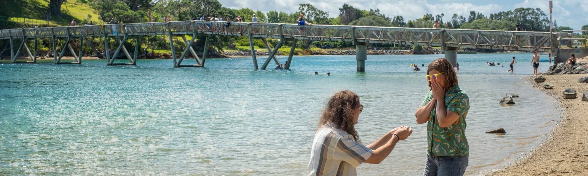 A man proposes to a shocked (happy shocked) woman by the footbridge between Pataua South and Pataua North, in Whangārei District. 