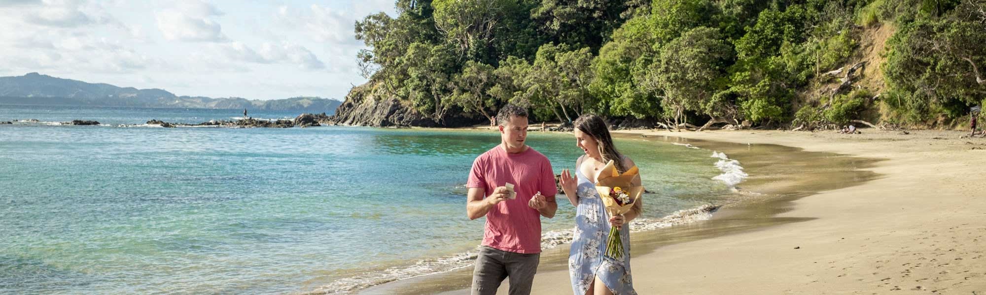 A man casually proposes to a woman on a stunning beach at Whale Bay, in the Whangārei District.